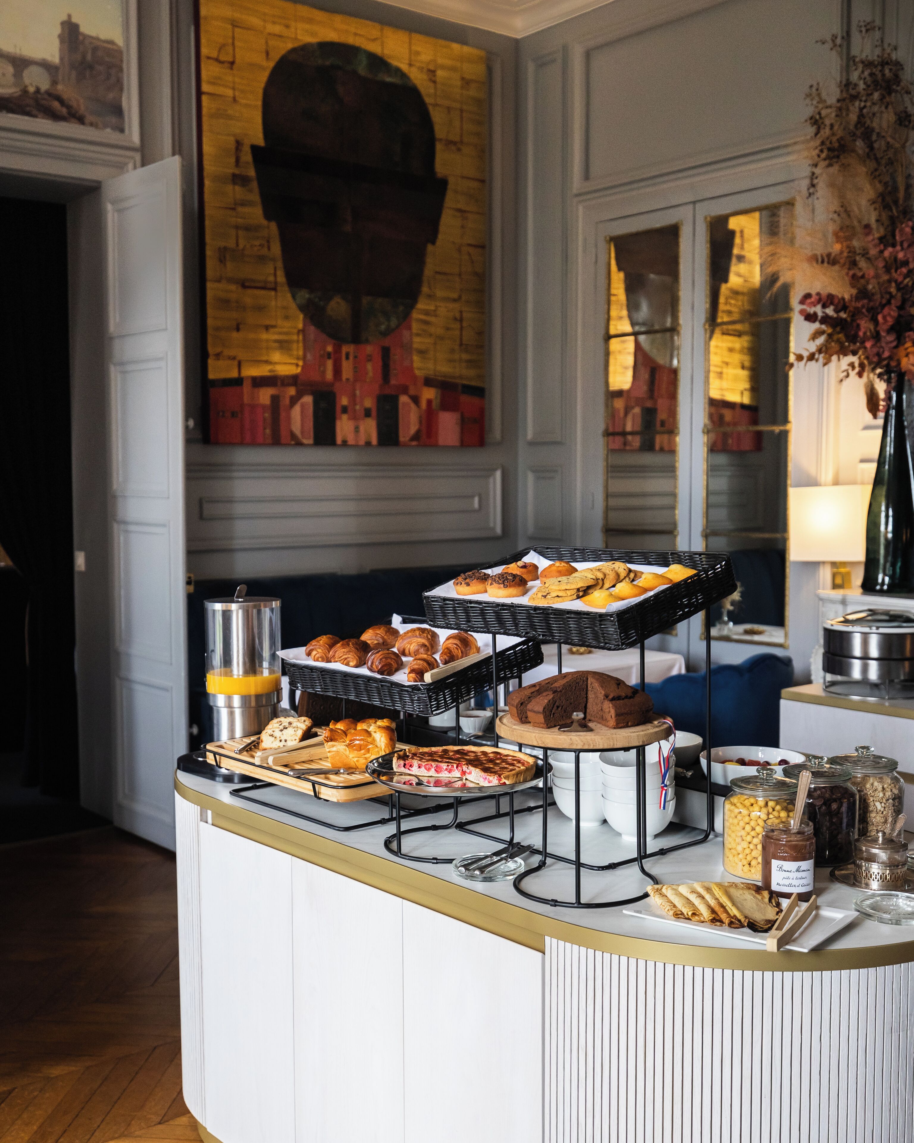 A buffet counter with various baked goods, including pastries and bread, and a coffee machine.