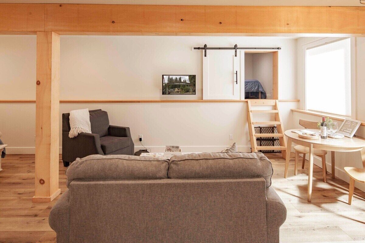 Una sala moderna con sofá, mesa de comedor y vista a un dormitorio.