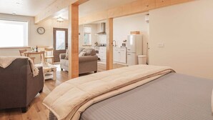 A cozy bedroom with a large bed, a grey sofa, and a wooden ceiling.