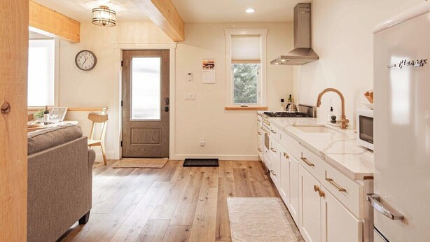 A modern kitchen with wooden flooring, white cabinets, and a built-in oven.