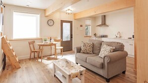 A cozy living room with a sofa, a coffee table, and a dining area with chairs and a small table.
