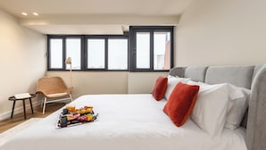 Habitación de hotel con una cama grande, una silla, una bandeja de desayuno y una ventana con persianas.