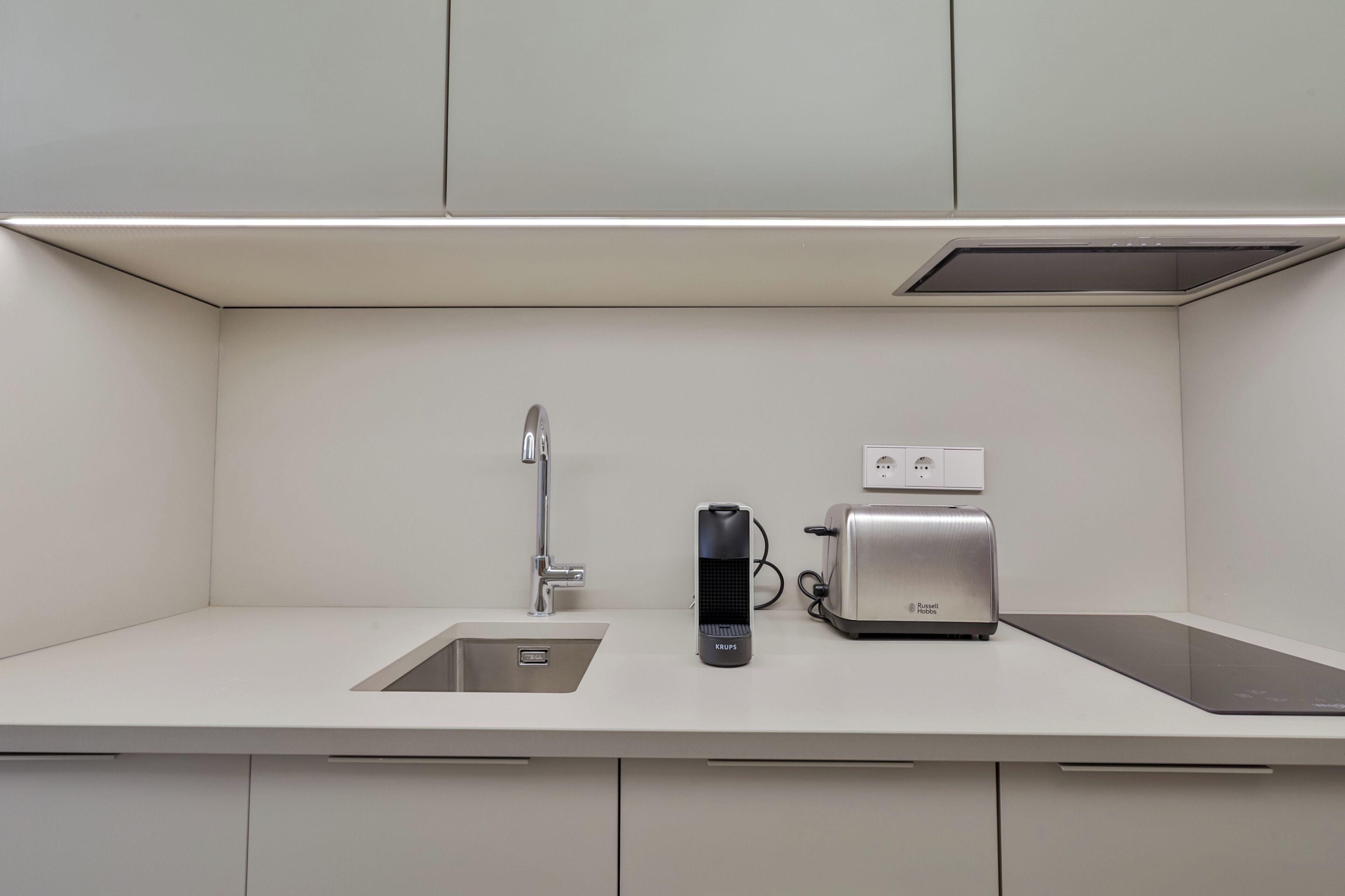 Een moderne keuken met een inbouwspoelbak, een koffiezetapparaat en een broodrooster.
