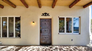 Un exterior rústico con puerta de madera, ventanas amplias y suelo de piedra.
