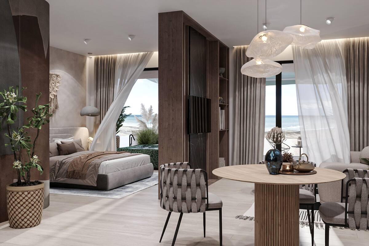 Un dormitorio moderno con una cama grande, una zona de comedor con una mesa redonda y vistas a la playa.