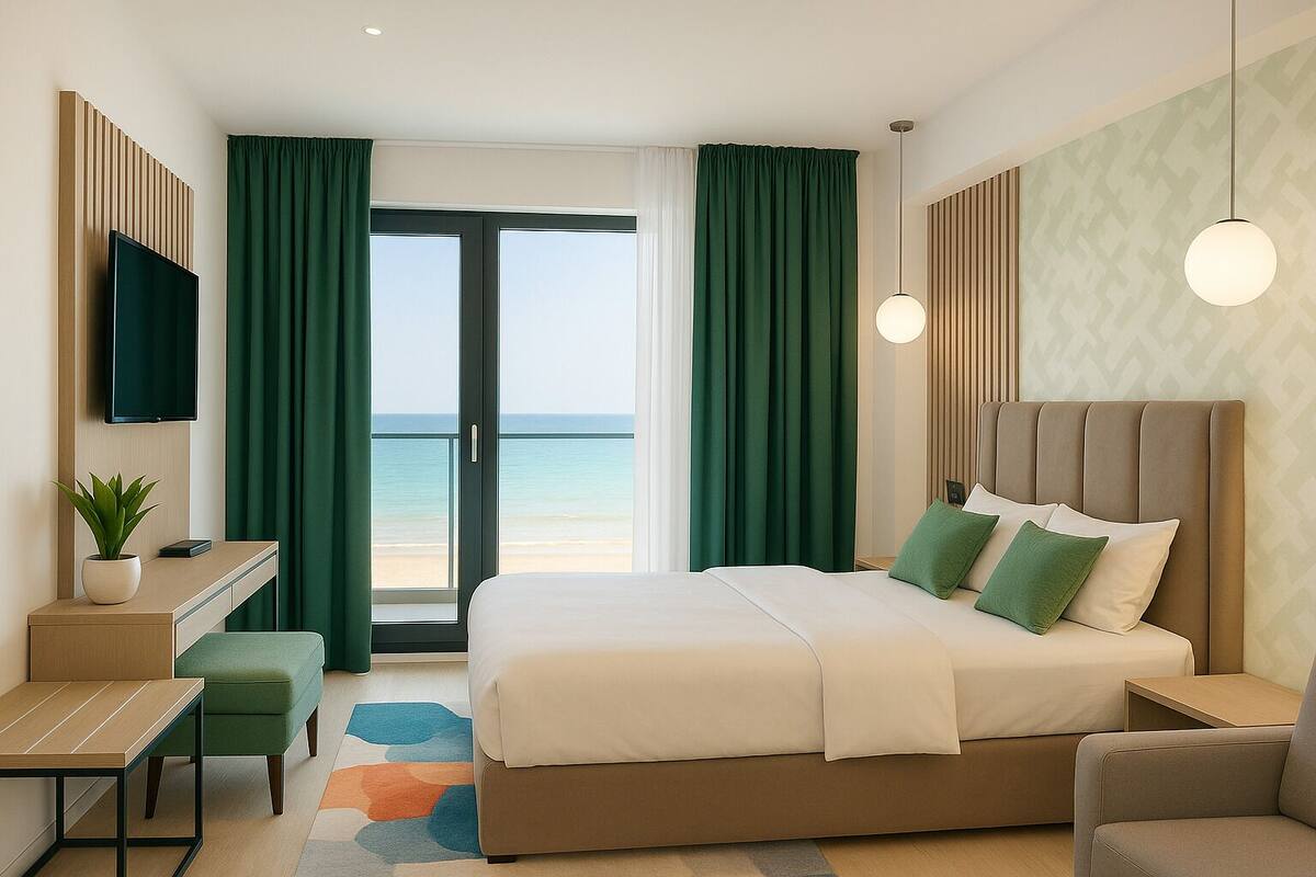 Habitación de hotel con una cama grande, escritorio, silla, televisión y vista a la playa.