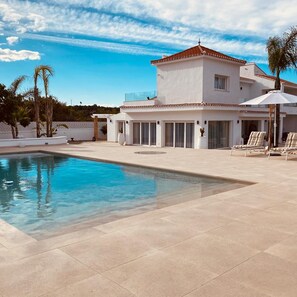 A modern house with a swimming pool, a patio with lounge chairs, and a clear blue sky. - Villa Las Palmeras in Alhaurin de la Torre (Alhaurin de la Torre)