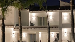 A two-story building with a balcony, palm trees, and outdoor seating. - Villa Las Palmeras in Alhaurin de la Torre (Alhaurin de la Torre)