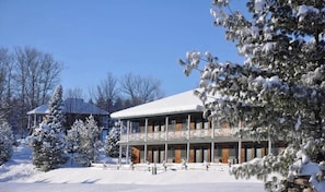 Ein Gebäude mit überdachter Veranda und schneebedeckten Bäumen.