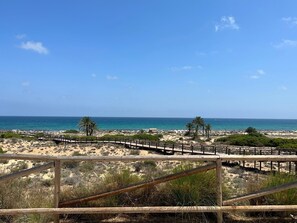 A beach with a wooden boardwalk leading to the water, surrounded by dunes and sparse vegetation. - Beautiful apartment, very well-equipped, air conditioning, Wi-Fi, satellite TV. (Alacant)