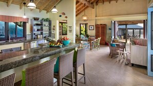 Uma cozinha espaçosa com balcão, cadeiras de vime e um espaço de jantar com vista.