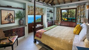 Quarto com uma cama grande, vista para o mar, teto de madeira e janela com cortinas.