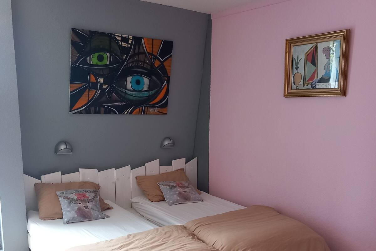 Een slaapkamer met twee bedden, een grijze muur en een roze muur.