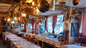A rustic dining area with long wooden tables, hanging lights, and various kitchen utensils. - Hôtel Restaurant Le Montlo 48 (Mont Lozere et Goulet)