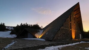 A stone structure with a sloped roof, possibly a historical building or monument, with a paved pathway leading to it. - Hôtel Restaurant Le Montlo 48 (Mont Lozere et Goulet)