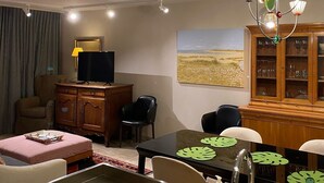Un salon moderne comprenant un coin repas, un téléviseur, un meuble et un tableau accroché au mur.