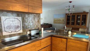 Une cuisine moderne avec des armoires en bois, un plan de travail en acier inoxydable et une cuisinière intégrée.