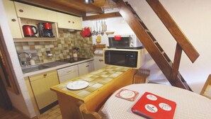 A compact kitchen with a wooden table, a microwave, and a coffee maker. - 100m from ski slopes, view village, balcony, fireplace or stove, tv, ski locker, 34m² (Champagny-en-Vanoise)