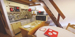 A compact kitchen with a wooden table, a microwave, and a coffee maker.