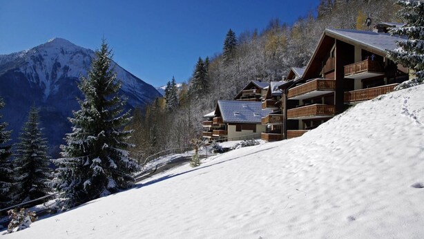 A mountain lodge with multiple balconies, surrounded by snow-covered trees and a mountain backdrop. - 100m from ski slopes, view village, balcony, fireplace or stove, tv, ski locker, 34m² (Champagny-en-Vanoise)