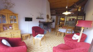 A cozy living room with red armchairs, a wooden cabinet, a fireplace, and a dining area with a table and chairs. - 100m from ski slopes, view village, balcony, fireplace or stove, tv, ski locker, 34m² (Champagny-en-Vanoise)
