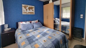 Un dormitorio con cama, armario, mesita de noche, un mapa en la pared y una ventana.