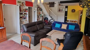 Una sala de estar con sofá, sillas, una mesa de centro, una estantería y una escalera.