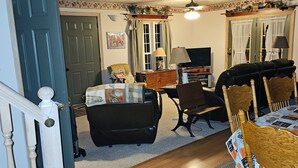A living room with a fireplace, a dining table with chairs, a television, and a staircase. - Cabin stay close to state park (Spring Mills)