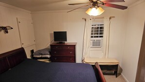 A bedroom with a bed, a dresser, a television, a window with curtains, and a ceiling fan. - Cabin stay close to state park (Spring Mills)