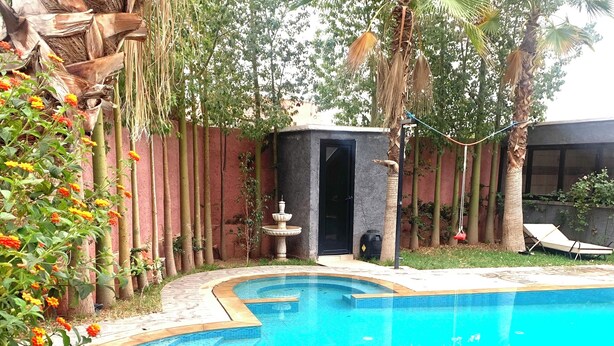 A swimming pool with a curved edge, surrounded by a tiled deck with a decorative pattern. - Splendide Villa, Marrakech (Marrakech)