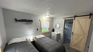 A bedroom with two beds, a small sink, a mirror, and a sliding door. - Fishermen’s Denn-Marblehead and Port Clinton  vacation area (Port Clinton)