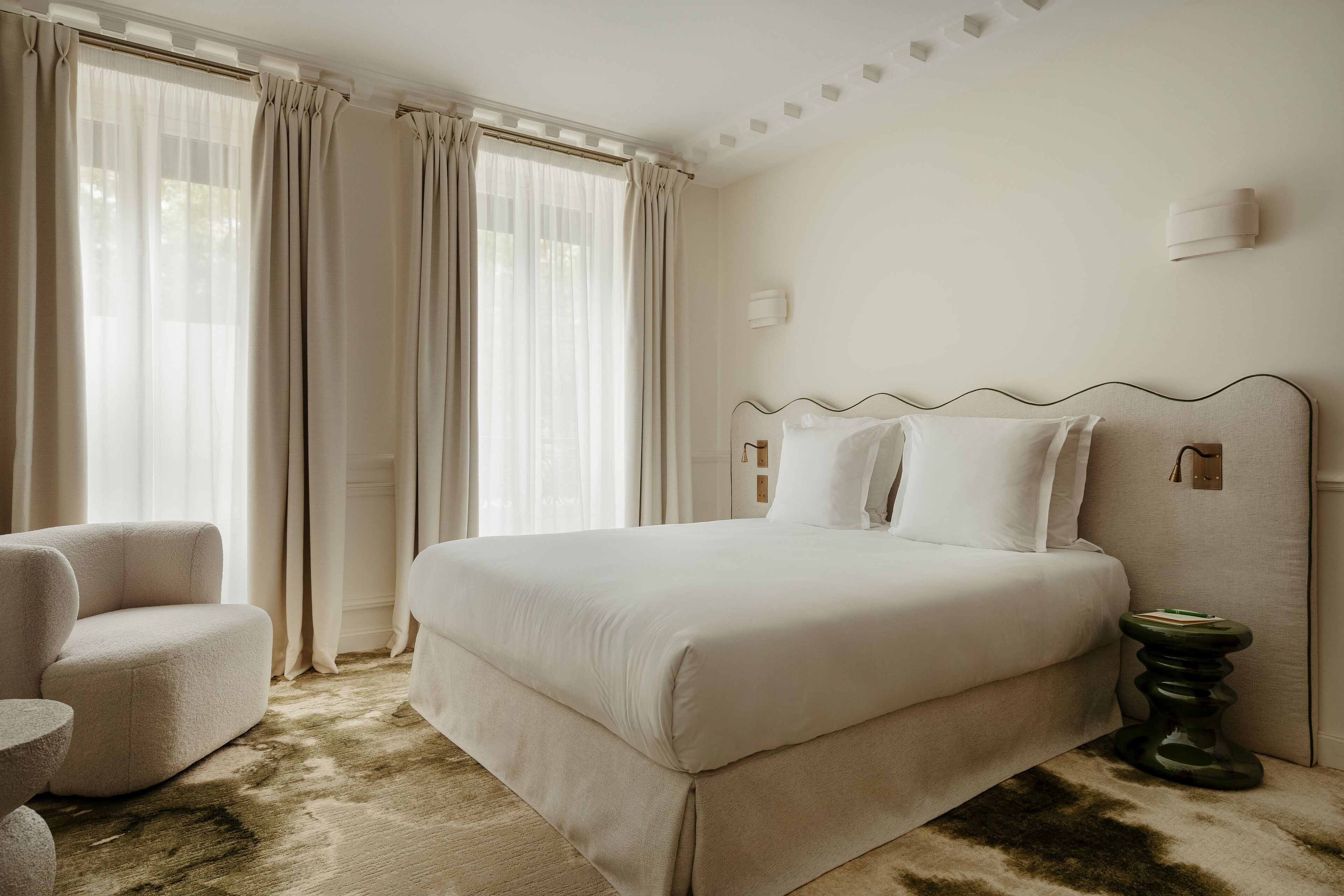 A hotel room with a large bed, a chair, and a small table.