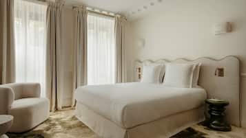 A hotel room with a large bed, a chair, and a small table.