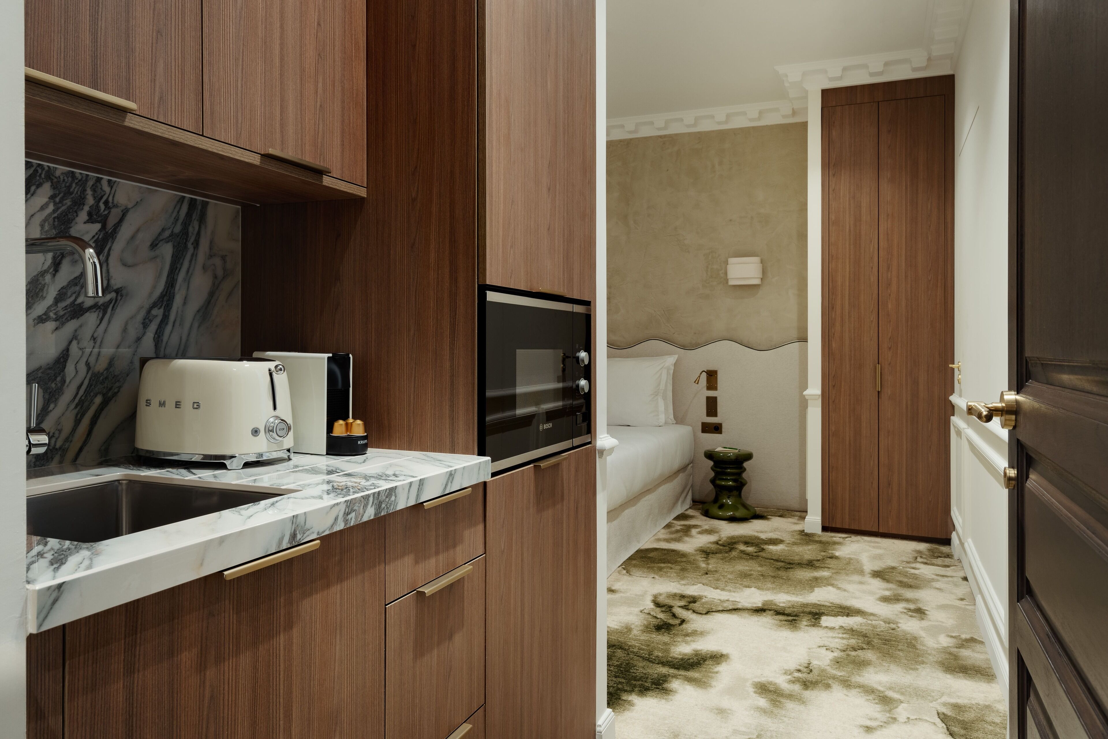 A compact kitchen with a marble countertop, a toaster, a microwave, and wooden cabinets.