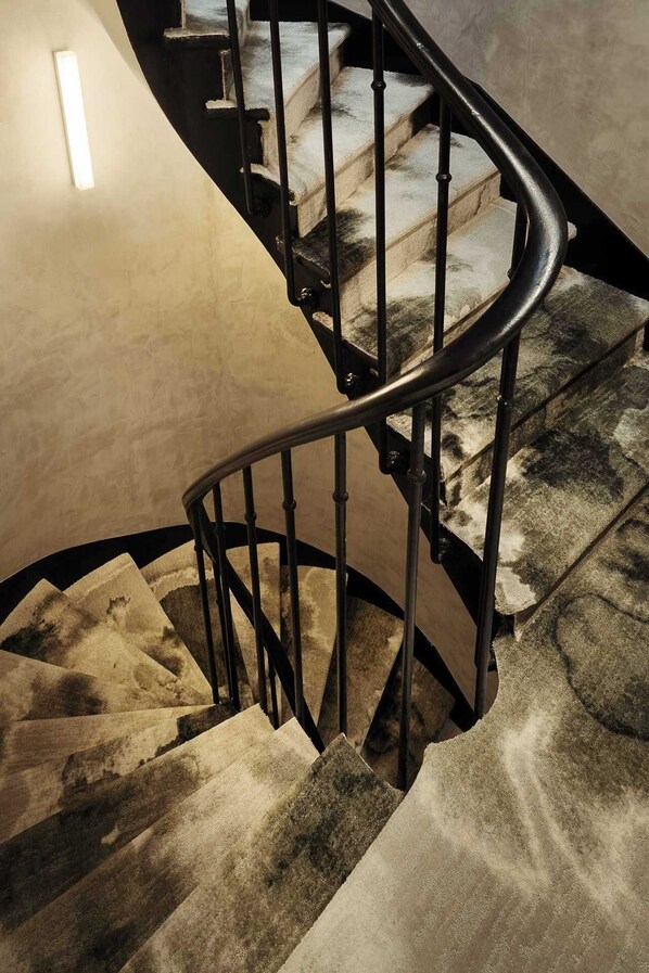 Un escalier en colimaçon doté d’une rampe et de marches recouvertes de moquette.