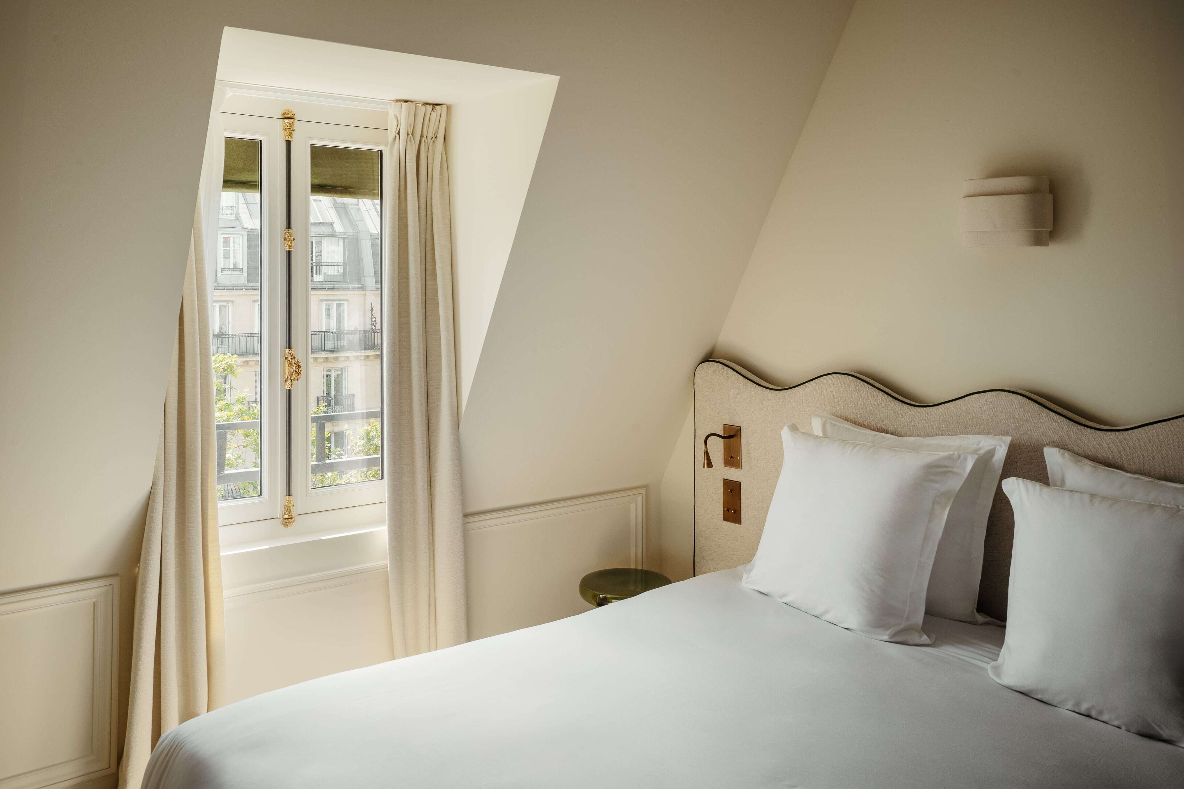 A bedroom with a large bed, a nightstand, and a window with curtains.