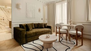 Ein modernes Wohnzimmer mit einem grünen Sofa, einem runden Couchtisch und einem weißen Teppich.