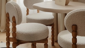 Ein Zimmer mit einem runden Tisch, vier Stühlen mit Holzbeinen und einer Vase auf dem Tisch.