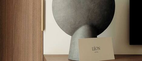 A modern sculpture on a wooden shelf with a card labeled "Léon Hotel".
