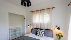 A bedroom with a bed, bedside lamps, a nightstand, a window with curtains, and a wardrobe. - LOLA COTTAGE - MI CASA TU CASA (Kyneton)