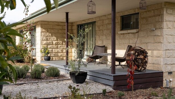 A stone building with a covered porch, outdoor seating, and potted plants. - LOLA COTTAGE - MI CASA TU CASA (Kyneton)