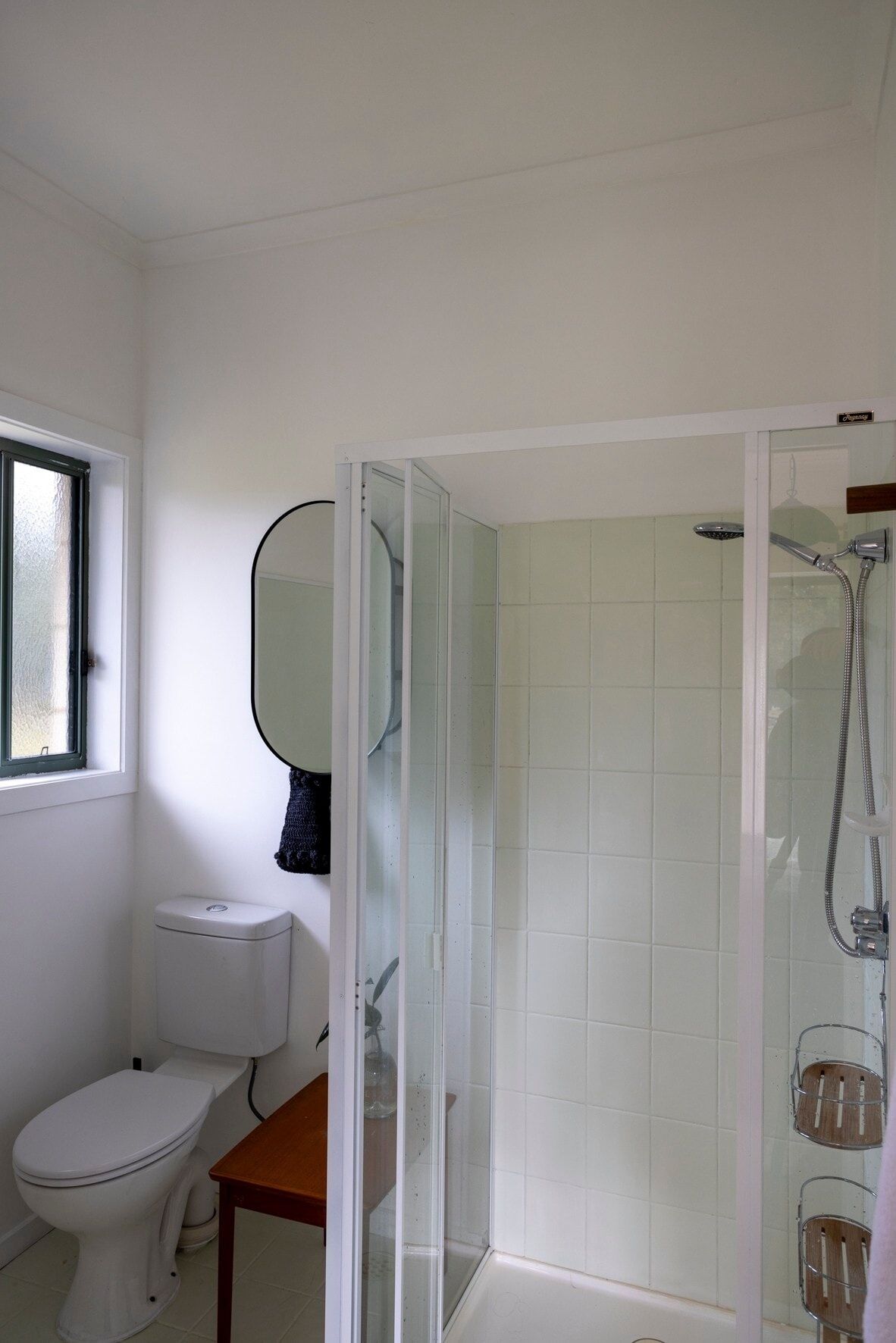 A bathroom with a toilet, a glass-enclosed shower, and a window.
