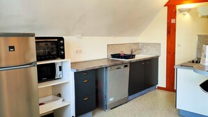 Une cuisine compacte équipée d’un réfrigérateur, d’un four à micro-ondes, d’un lave-vaisselle et d’un petit coin repas avec un tabouret de bar.