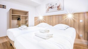 A hotel room with two beds, wooden headboard, a wooden wardrobe, and a polar bear artwork on the wall. - Wifi, ski-in/ski-out & foot of the slopes, 3rd floor, view ski slopes, fitness, swimming pool, sauna (La Rosière Montvalezan)