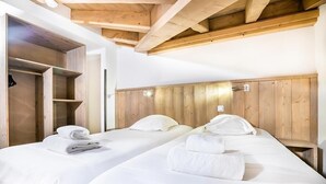 Una habitación de hotel con dos camas, cabeceros de madera y un armario empotrado.