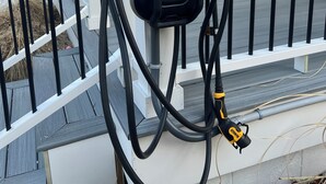 A black DeWalt power tool with a yellow label, connected to a white railing.