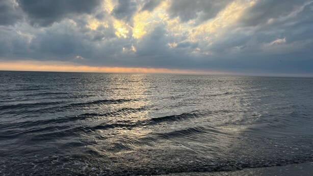 A calm sea with sunlight reflecting off the water.