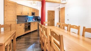 A kitchen with wooden cabinets, a dining table, and chairs.