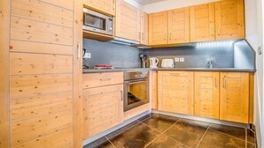 Une cuisine compacte avec des meubles en bois, un four à micro-ondes, une bouilloire et un évier.