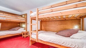 Une chambre avec deux lits superposés, chacun doté d’une tête de lit en bois et de draps blancs.